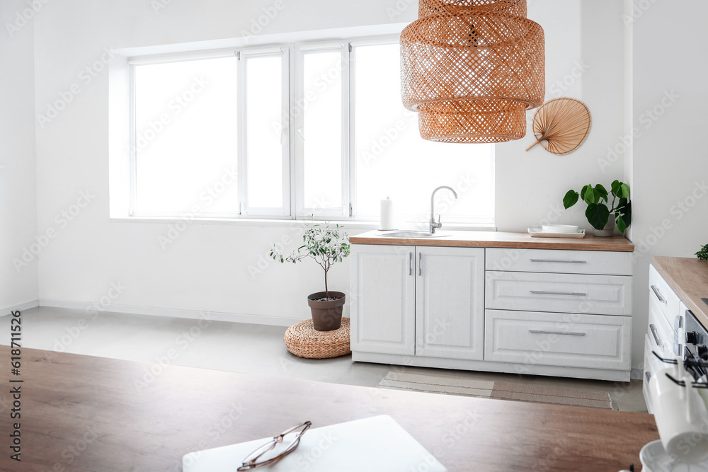 Interior of light kitchen with white counters near window