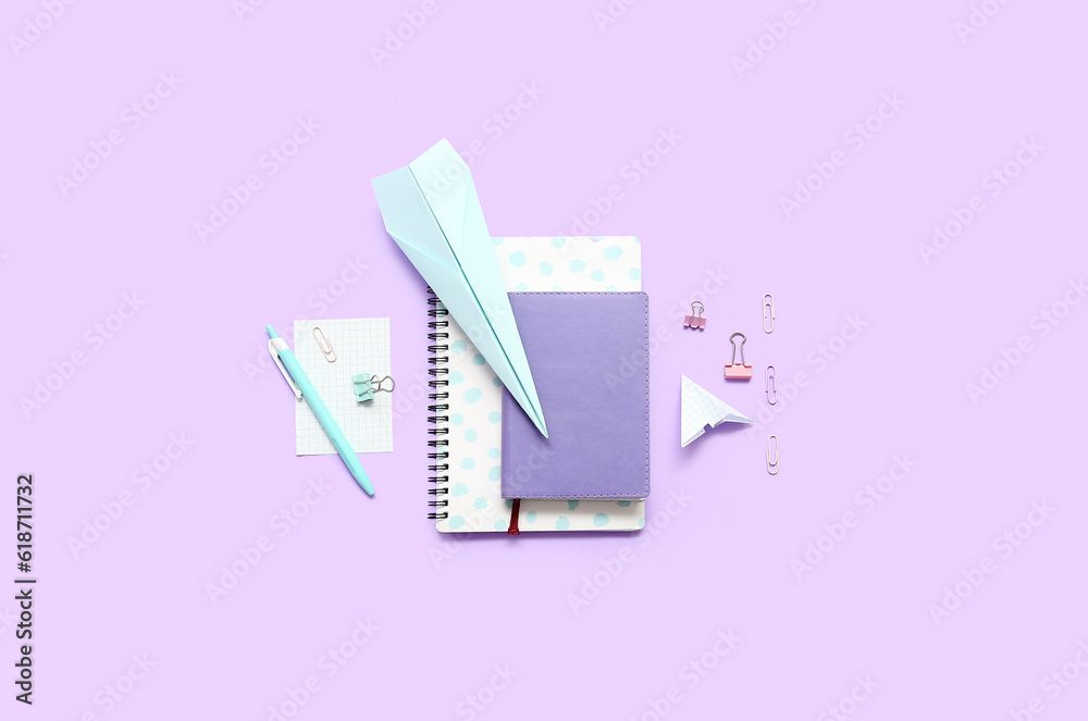 Notebooks, paper planes and school stationery on purple background