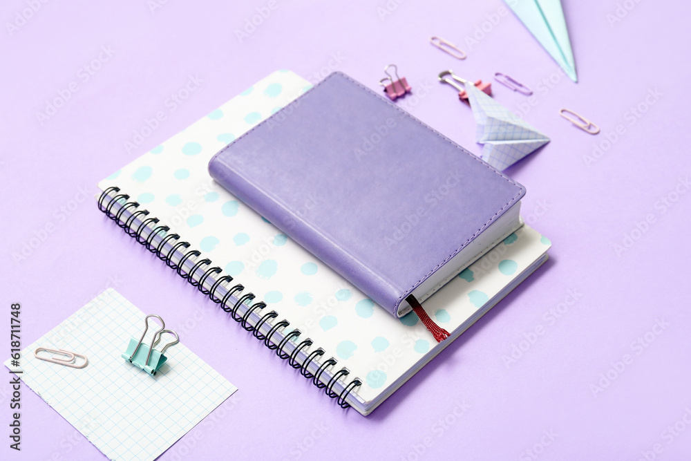 Notebooks, paper planes and school stationery on purple background, closeup