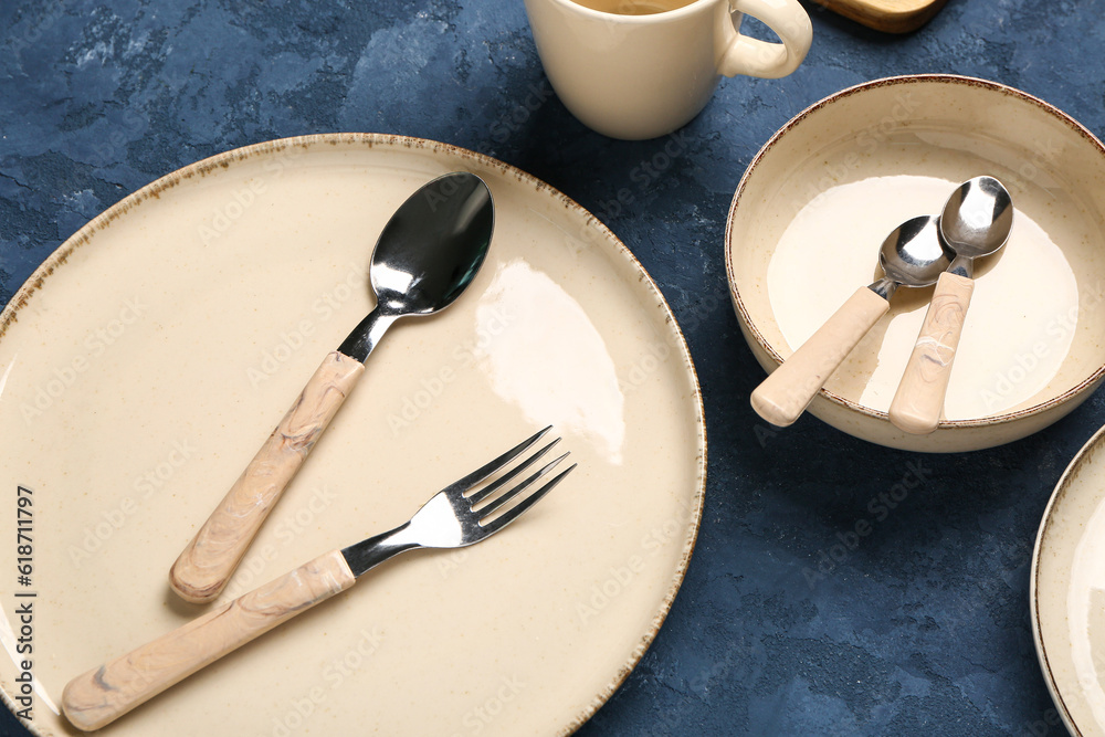 Clean plates, bowl and cutlery on blue table