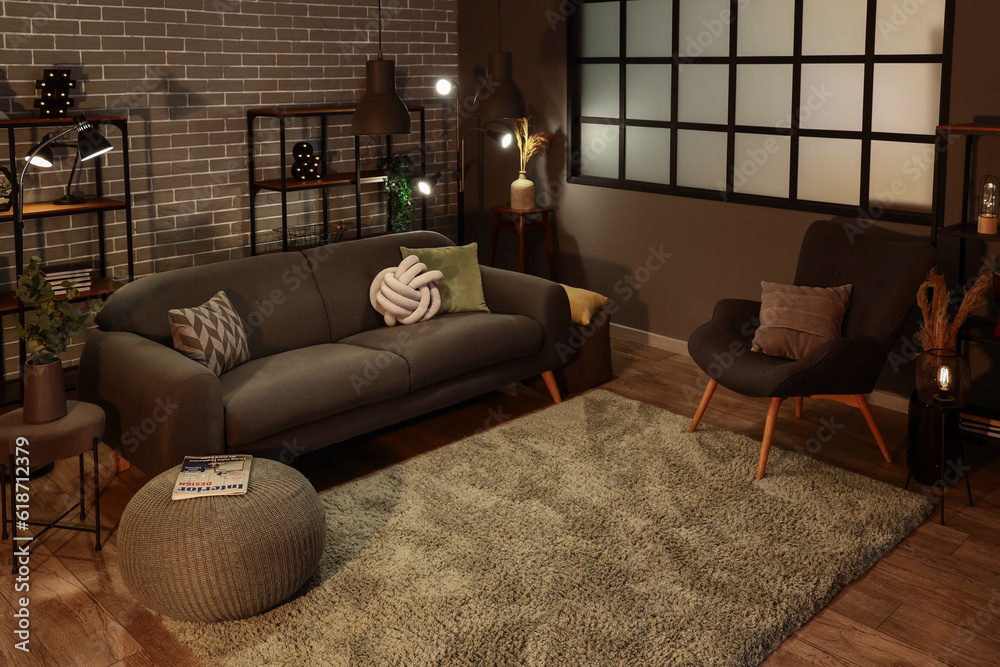 Interior of dark living room with cozy grey sofa and glowing lamps