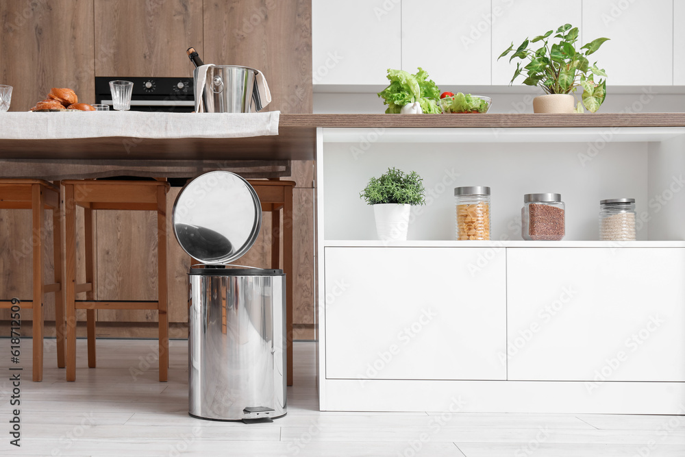 Opened trash bin in interior of light kitchen