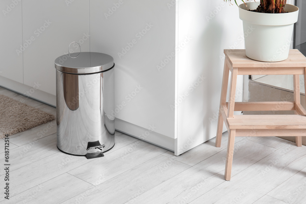 Metallic trash bin in interior of light kitchen