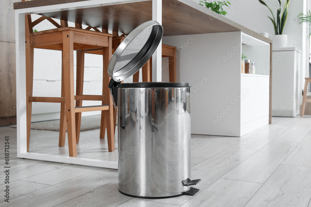 Opened trash bin in interior of light kitchen