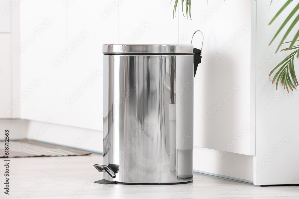 Metallic trash bin in interior of light kitchen