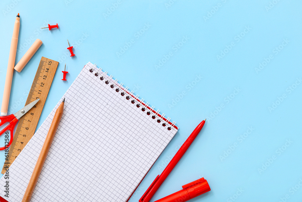 Blank notebook with different stationery on blue background