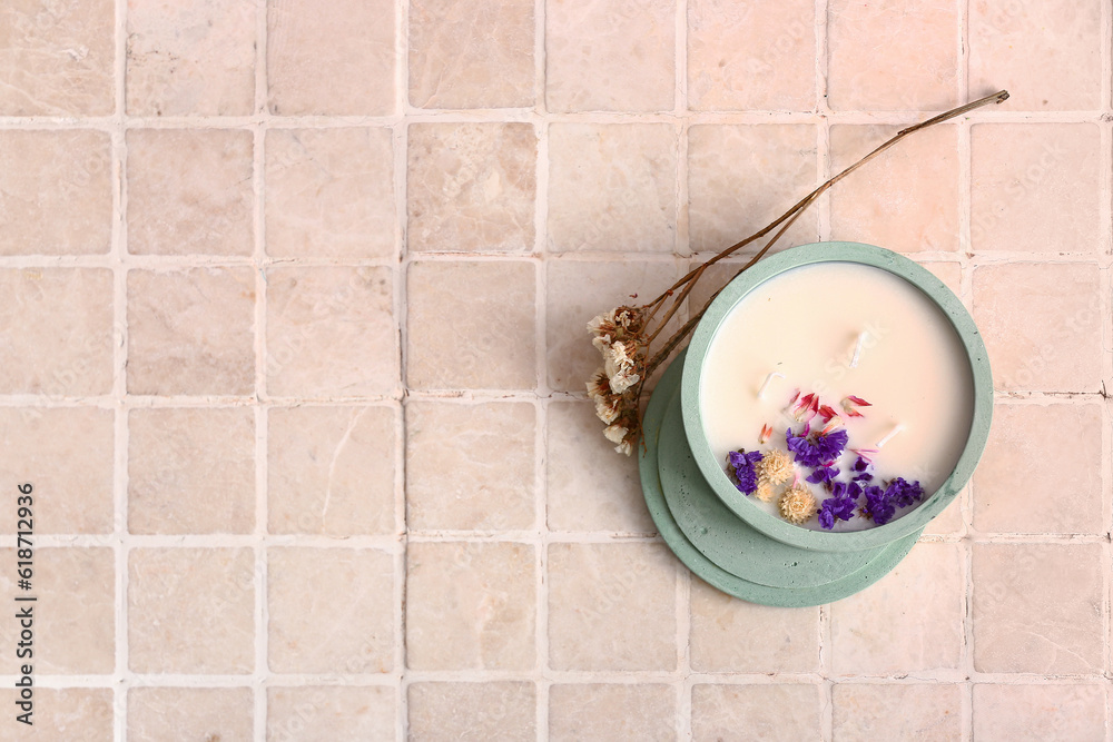 Holder with candle and flowers on beige tile background