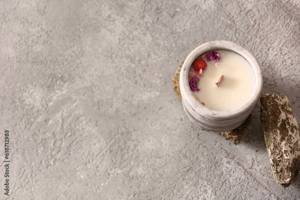 Holder with candle and stones on grey background