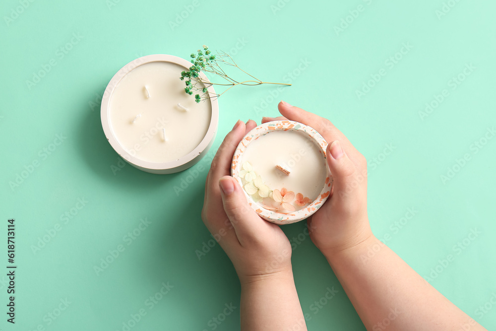 Female hands with candles on turquoise background