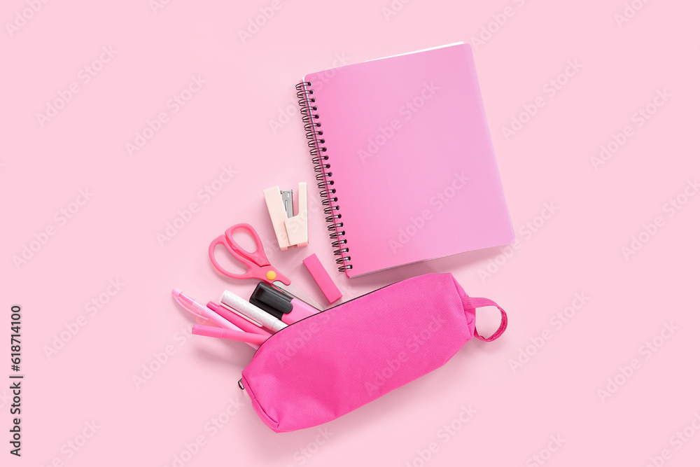 Notebook and pencil case with different stationery on pink background