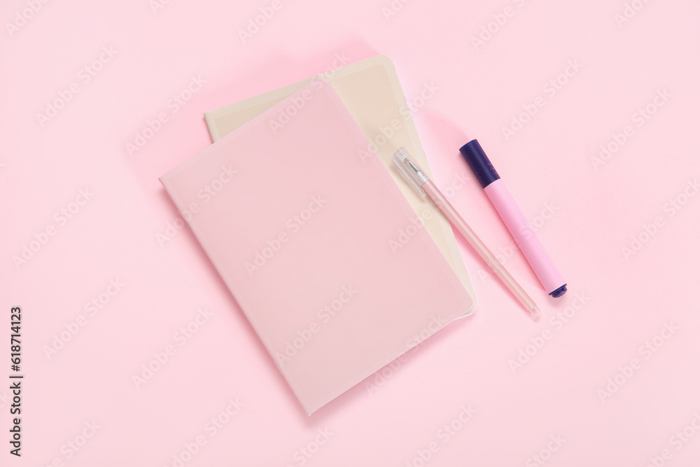 Notebook with pen and marker on pink background