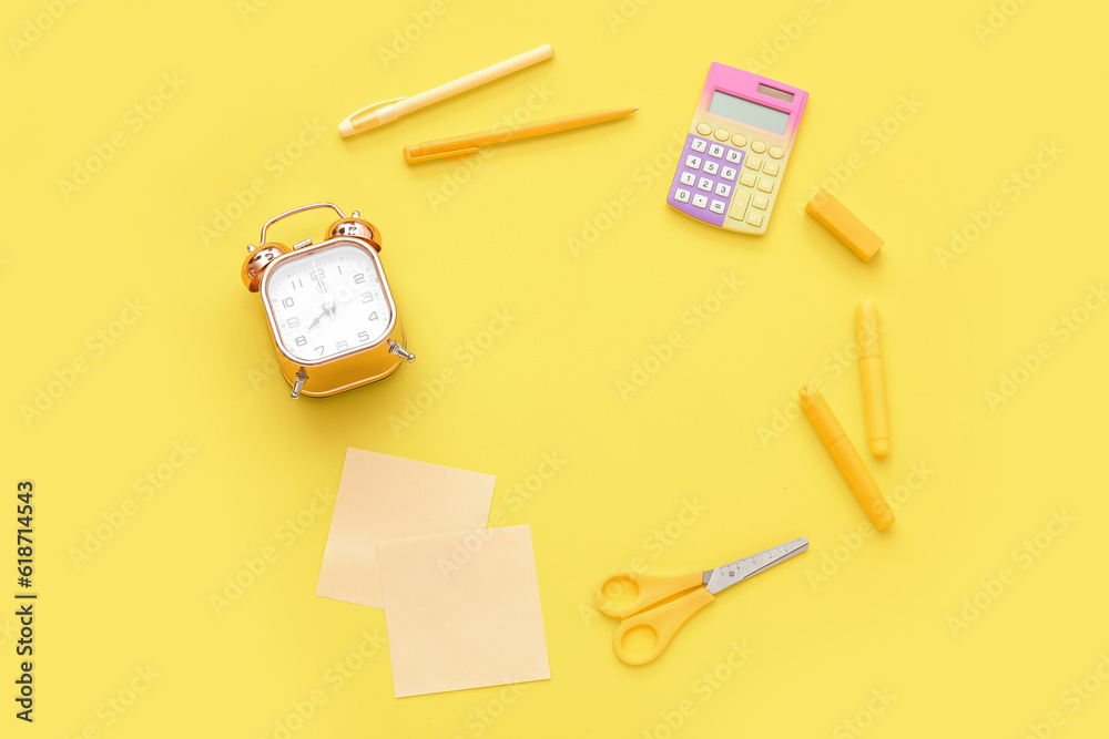 Frame made of alarm clock, calculator and different stationery on yellow background