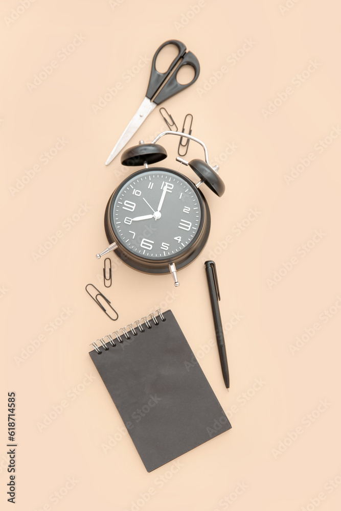 Alarm clock with different stationery on pale orange background