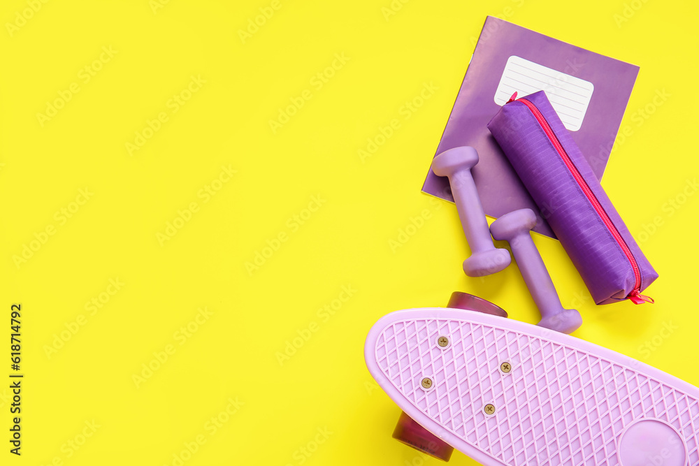 Skateboard with dumbbells, pencil case and notebook on yellow background