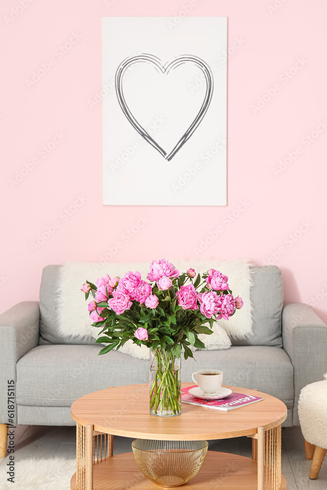 Vase of pink peonies on coffee table with couch in living room