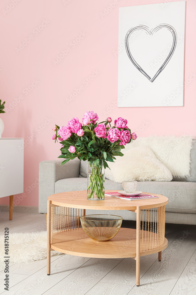 Vase of pink peonies on coffee table with couch in living room