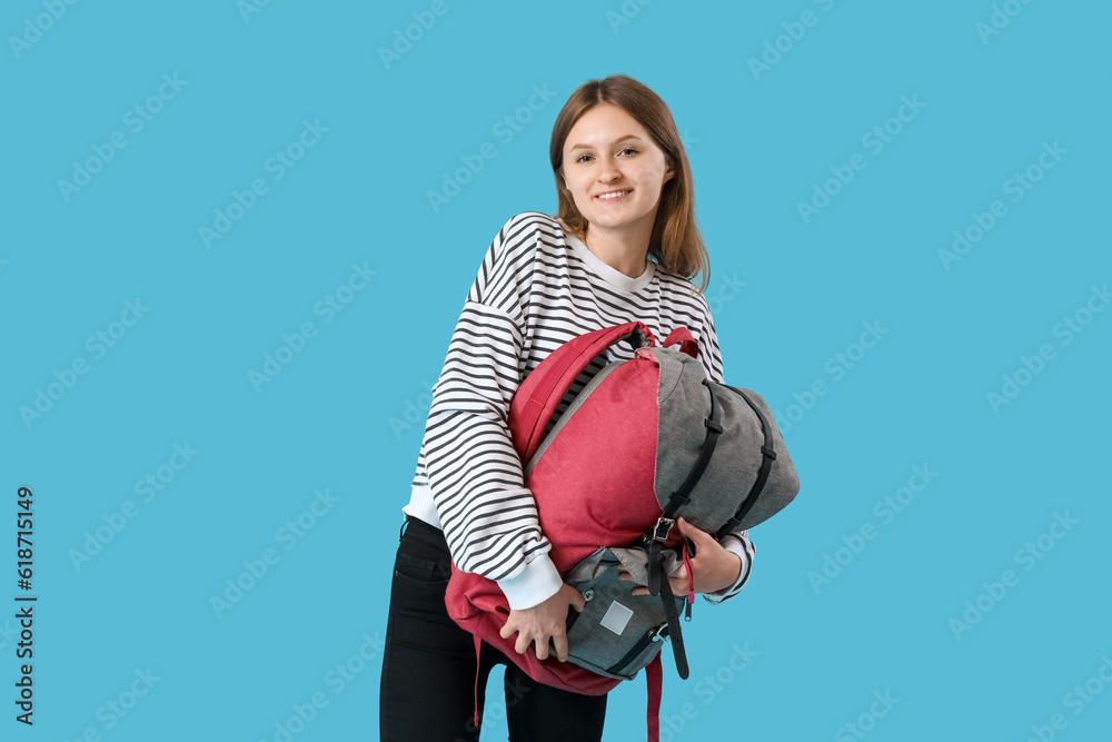 Female student with backpack on blue background