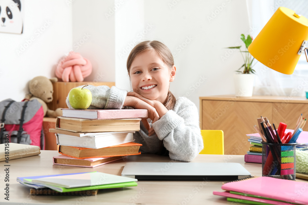 Little girl with stack of books doing lessons at home