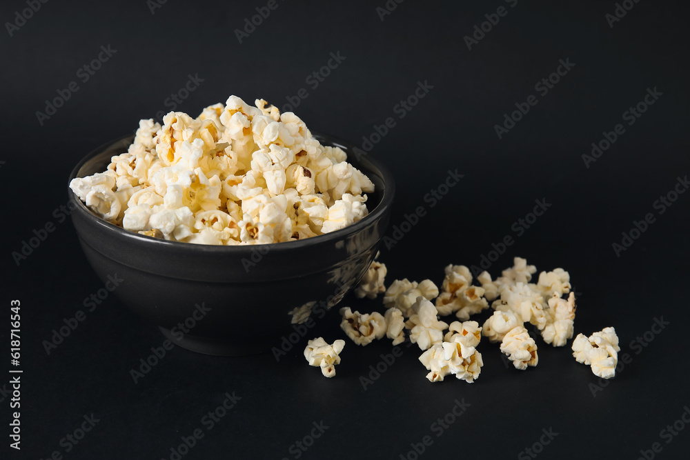 Bowl with tasty popcorn on black background