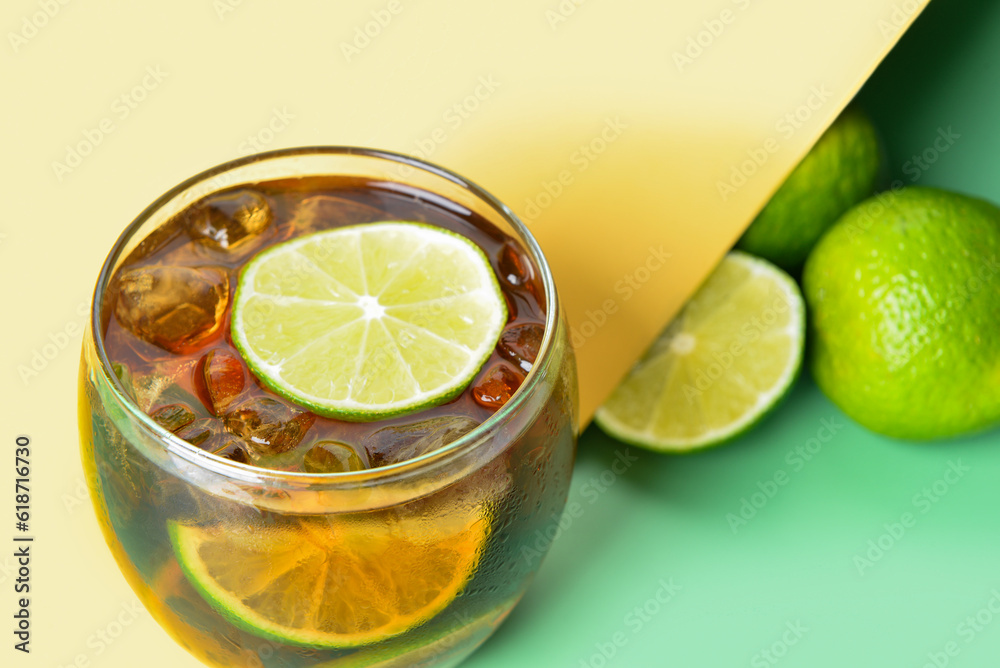 Glass of cold Cuba Libre cocktail on color background