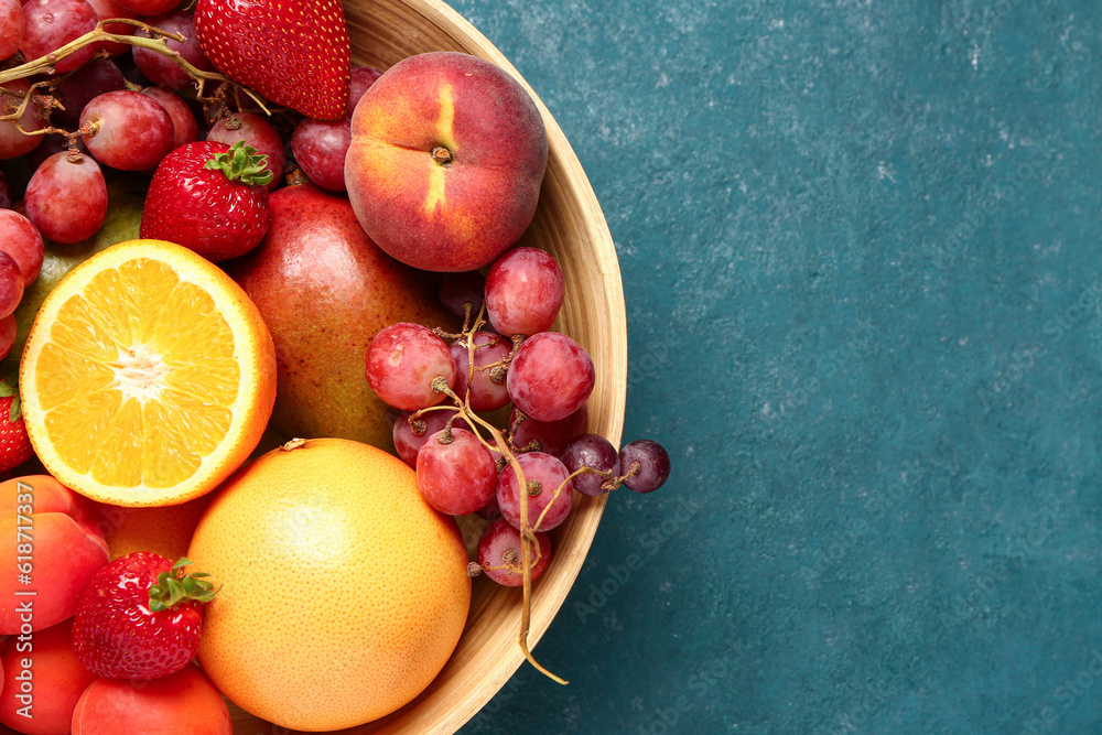 Bowl with different fresh fruits on blue background