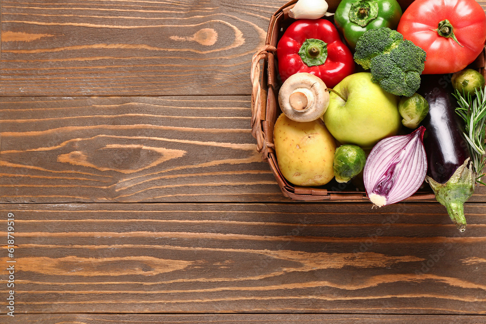 Wicker basket with fresh ripe vegetables on wooden background