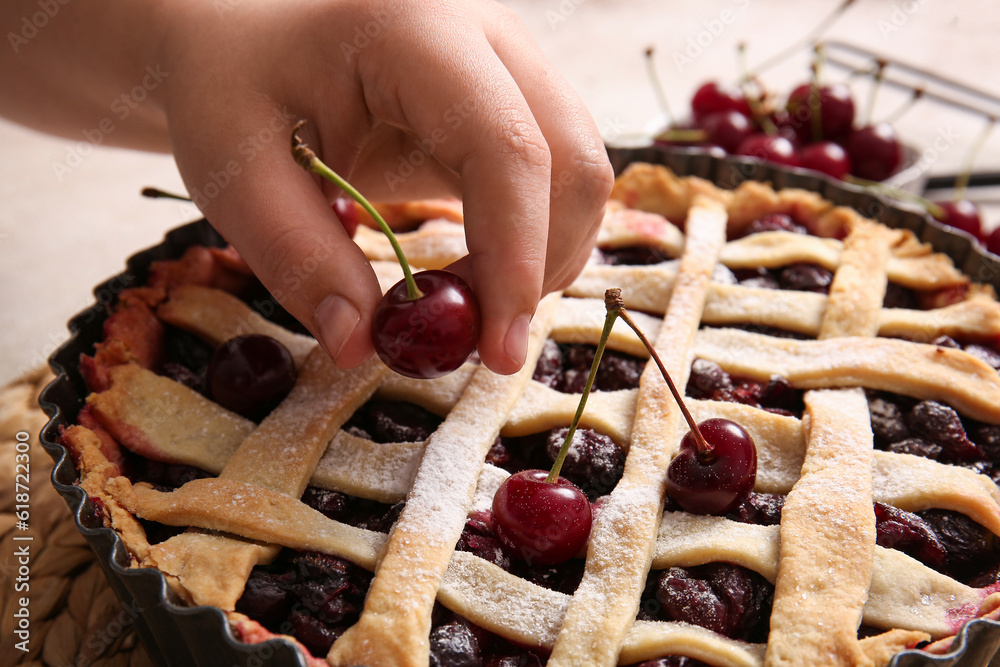 Woman decorating tasty cherry pie, closeup