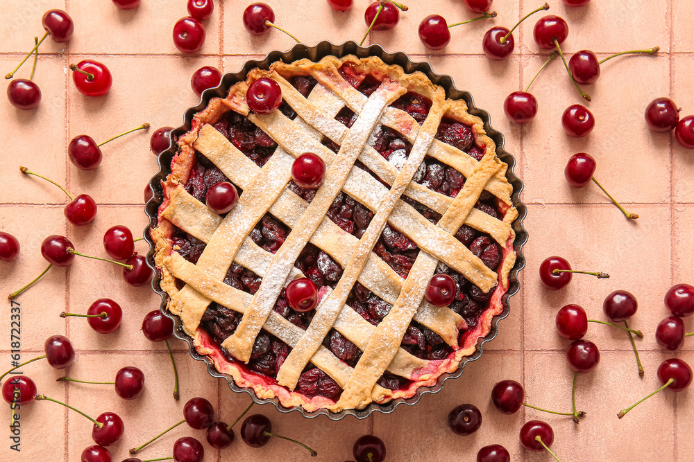 Baking dish with tasty cherry pie on pink tile background