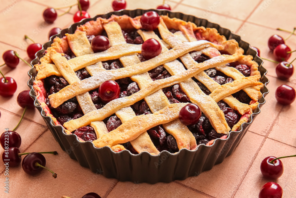 Baking dish with tasty cherry pie on pink tile background