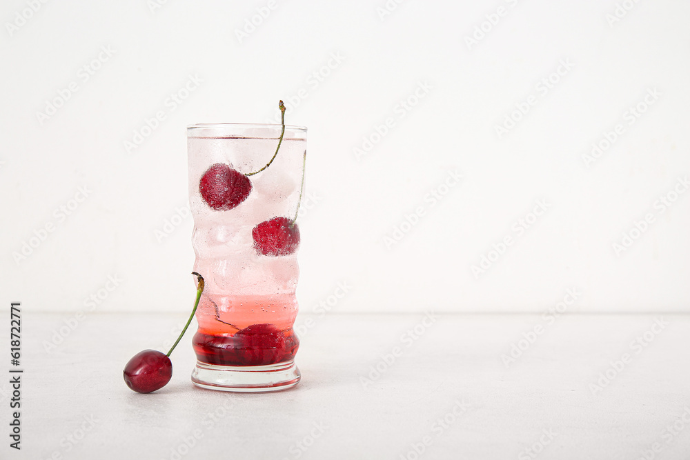 Glass of tasty cherry lemonade on white background