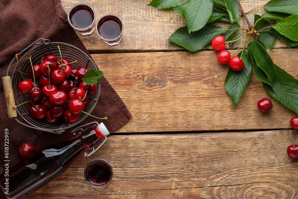 Shots and bottle with sweet cherry liqueur on wooden background