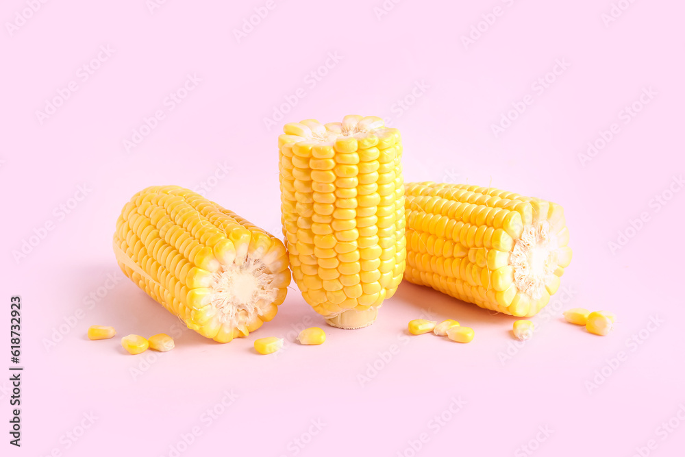 Cut fresh corn cobs and seeds on pink background