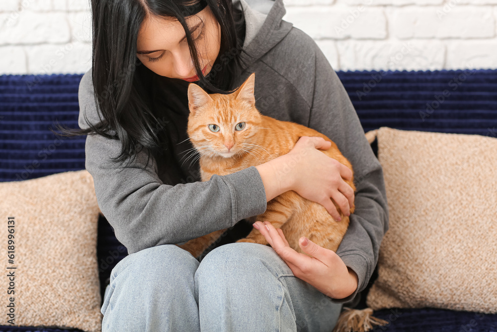 Woman with ginger cat sitting on sofa at home, closeup