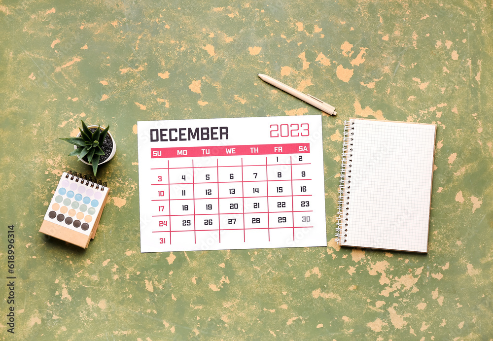 Calendar, notebook, pen, houseplant and color palette on green table