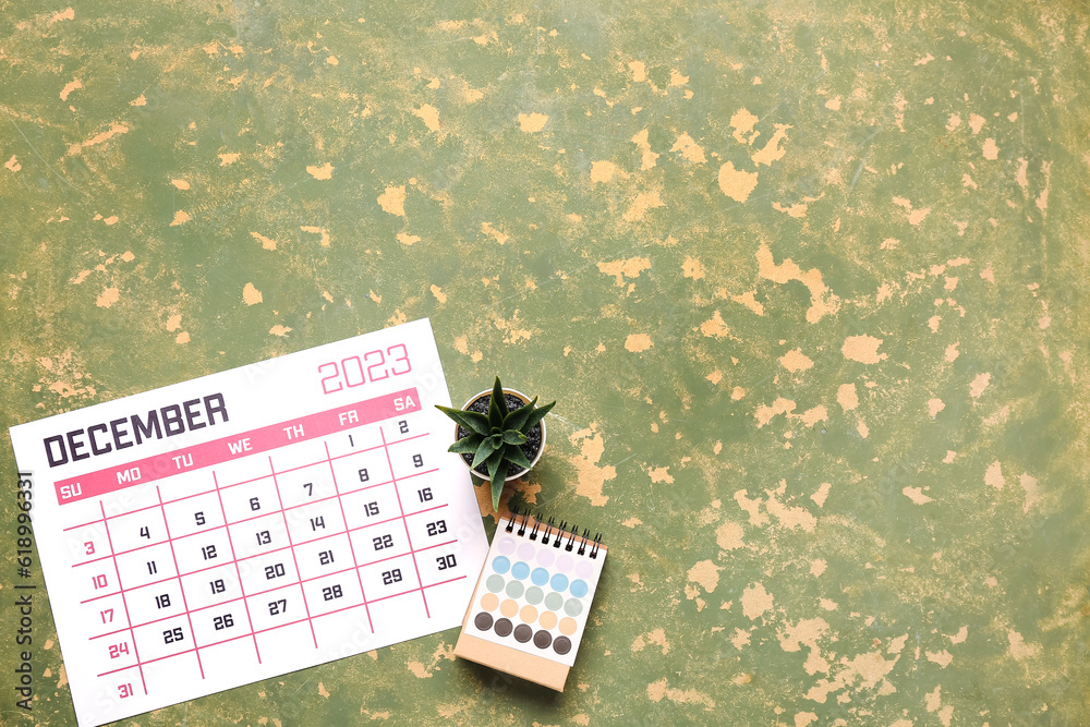 Calendar, houseplant and color palette on green table