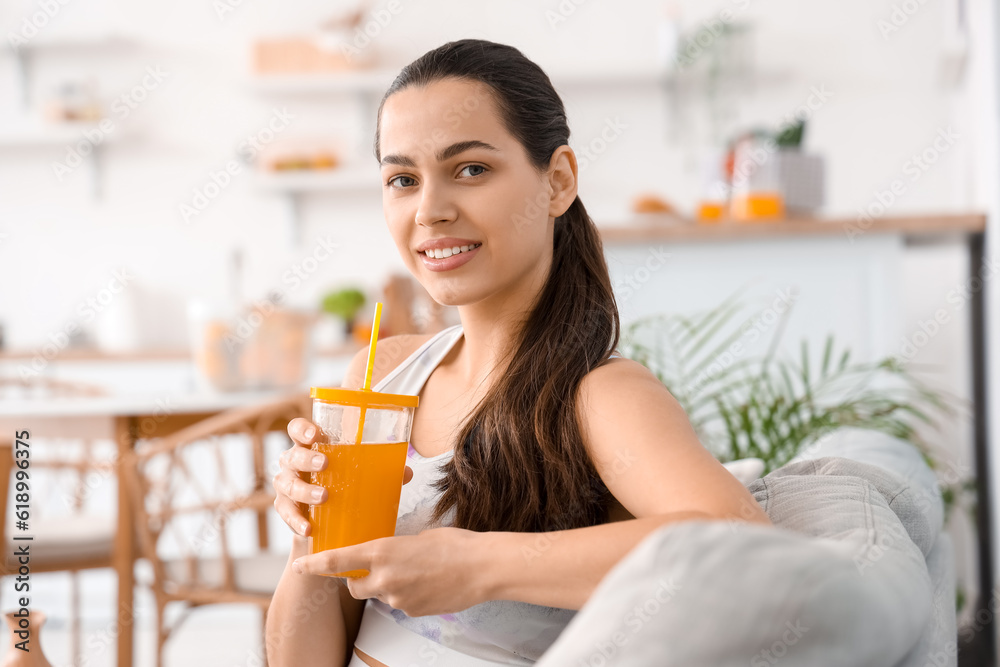 Sporty young woman with glass of vegetable juice in kitchen