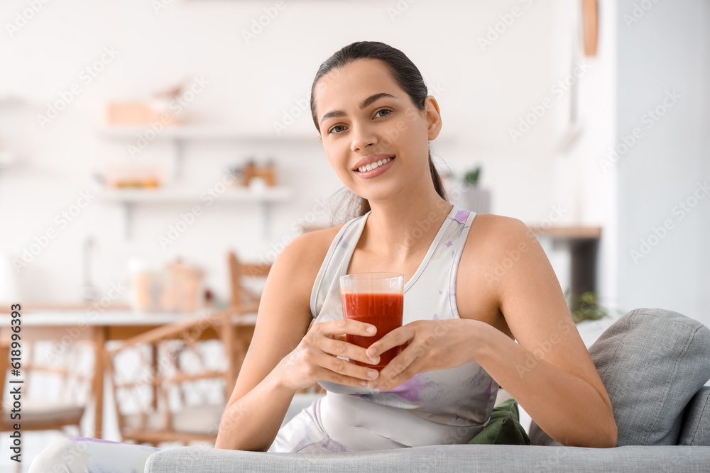 Sporty young woman with glass of vegetable juice in kitchen