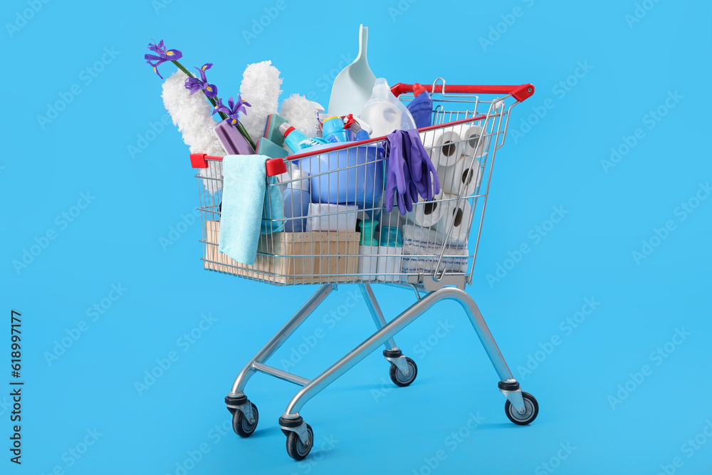 Shopping cart full of cleaning supplies and purple flowers on blue background