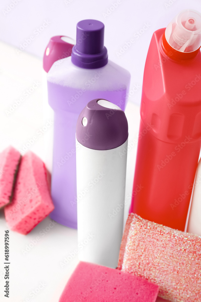 Different cleaning supplies on light wooden table, closeup