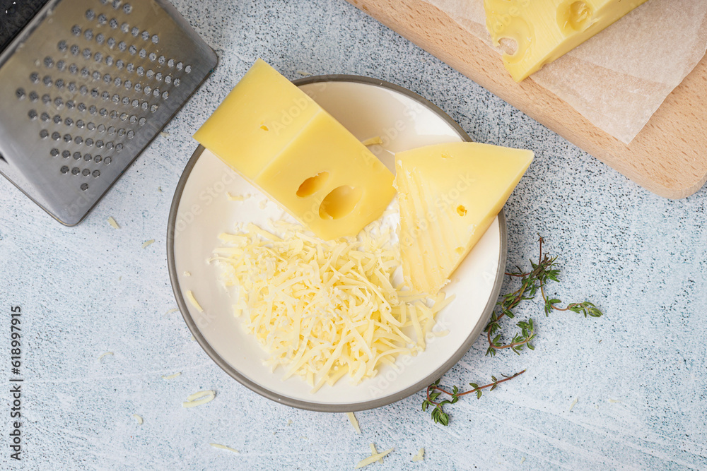 Plate and board with pieces of Swiss cheese on white table