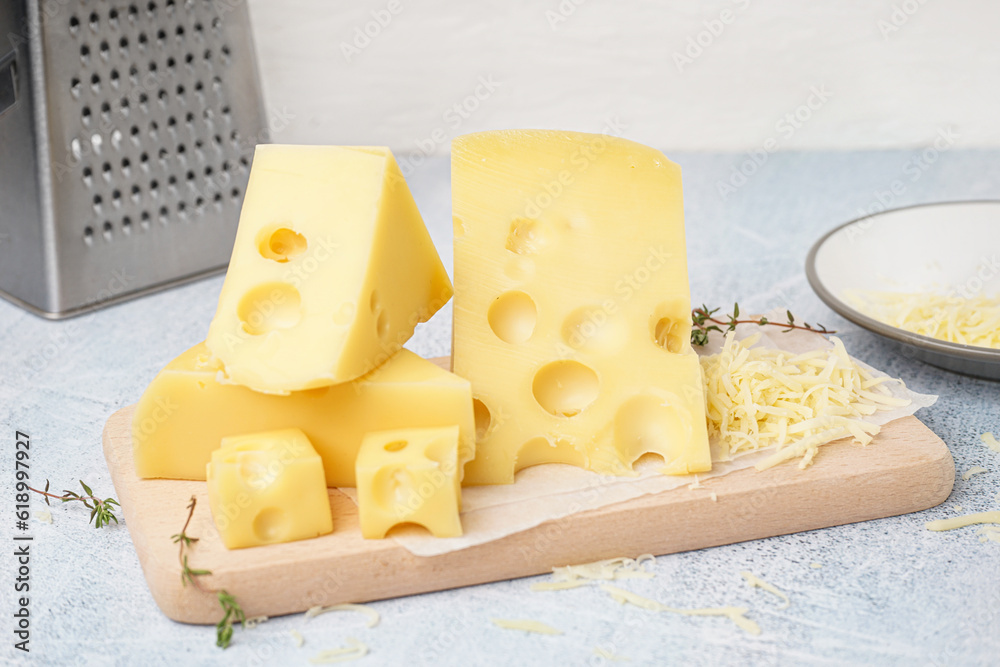 Board and plate with pieces of Swiss cheese on white table