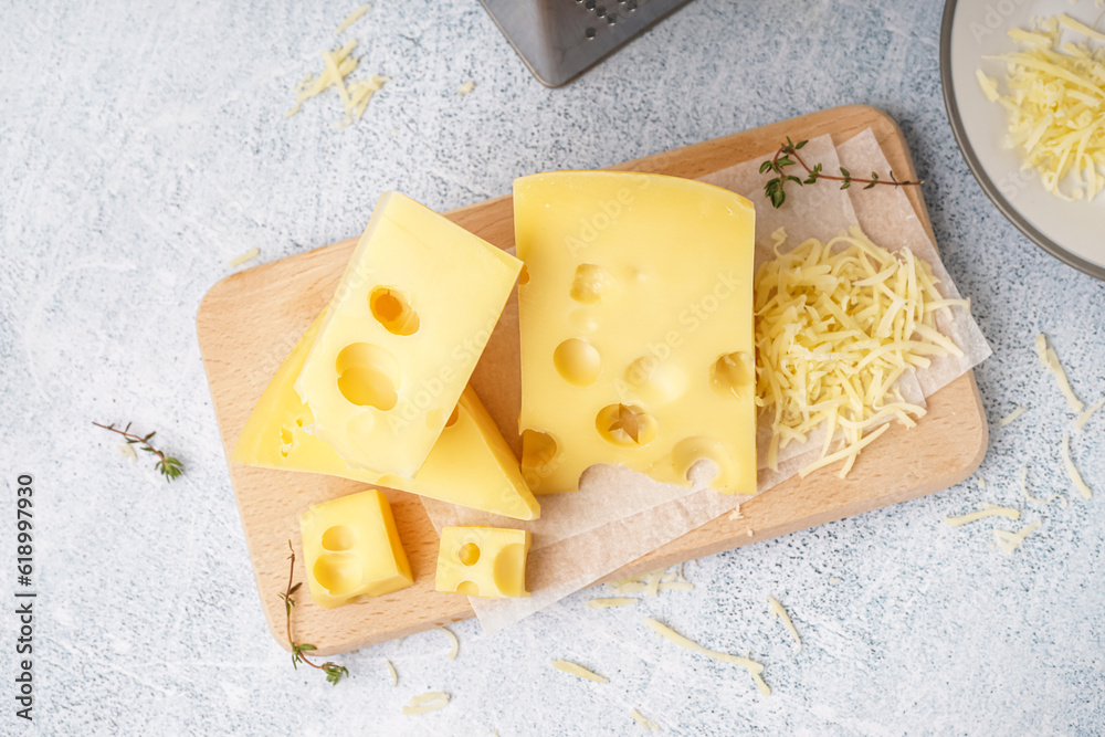 Board and plate with pieces of Swiss cheese on white table