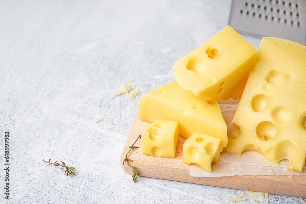 Board with pieces of Swiss cheese on white table