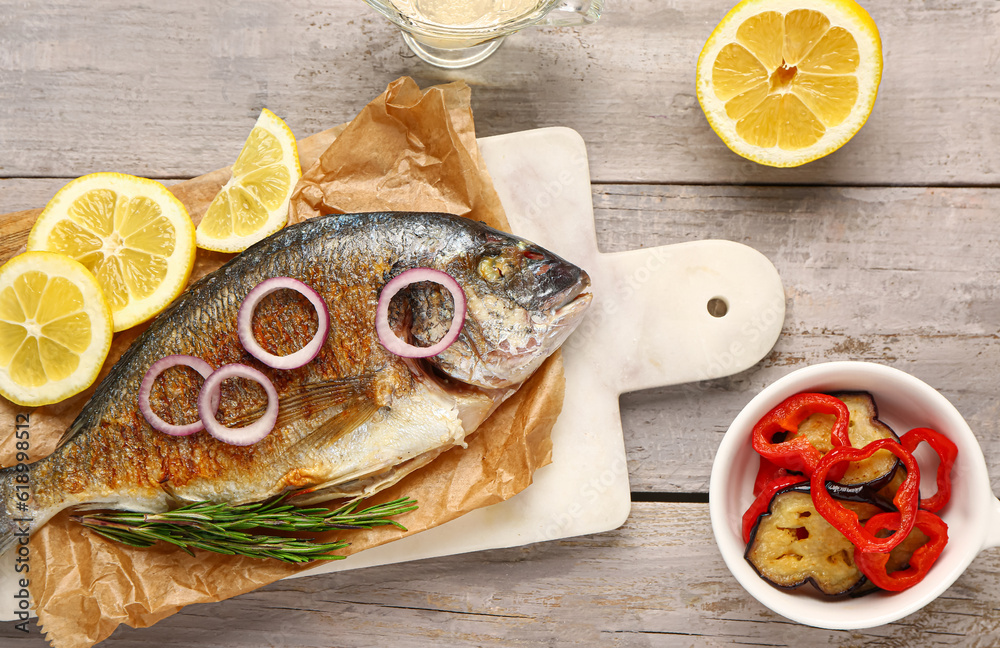 Board with tasty grilled dorado fish on grey wooden background