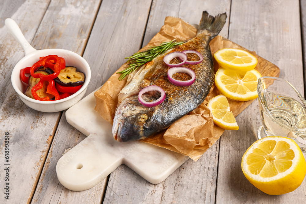 Board with tasty grilled dorado fish on grey wooden background