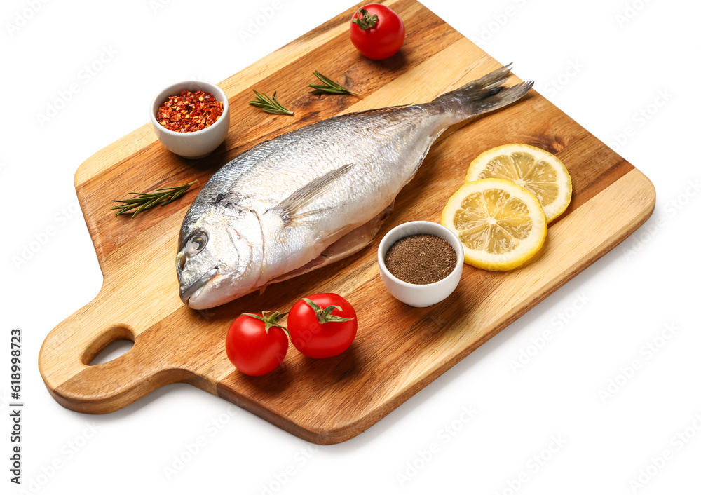 Wooden board of raw dorado fish with lemon and tomatoes on white background