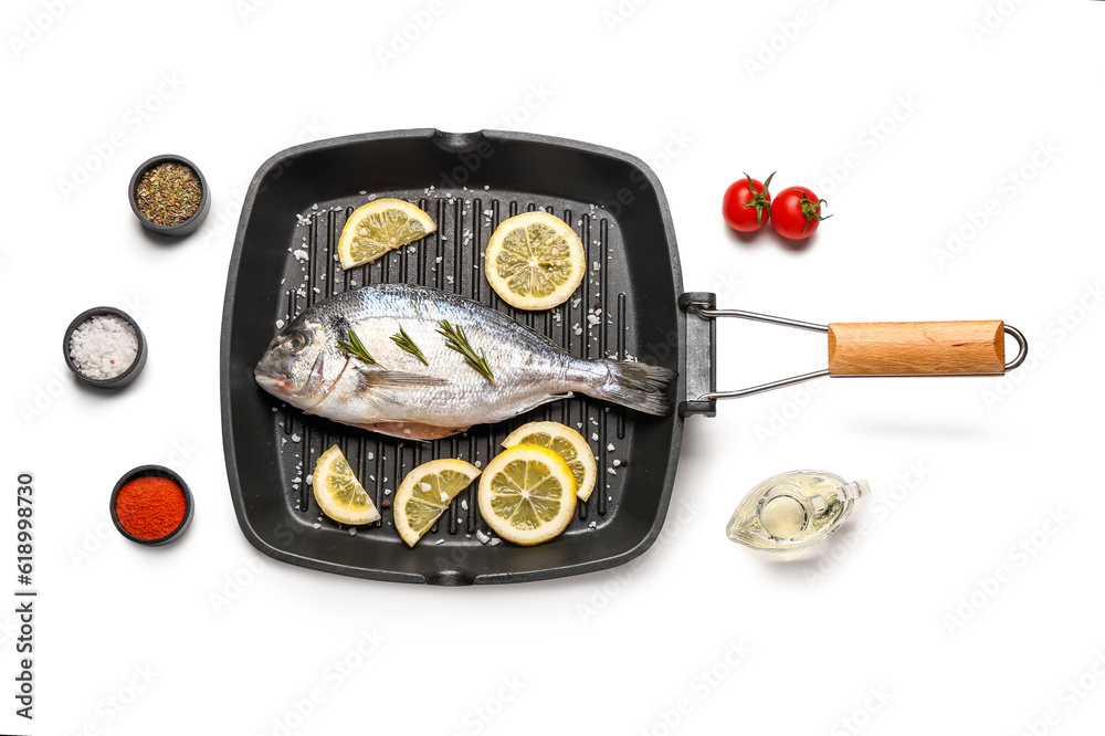 Grill pan of raw dorado fish with lemon and spices and on white background