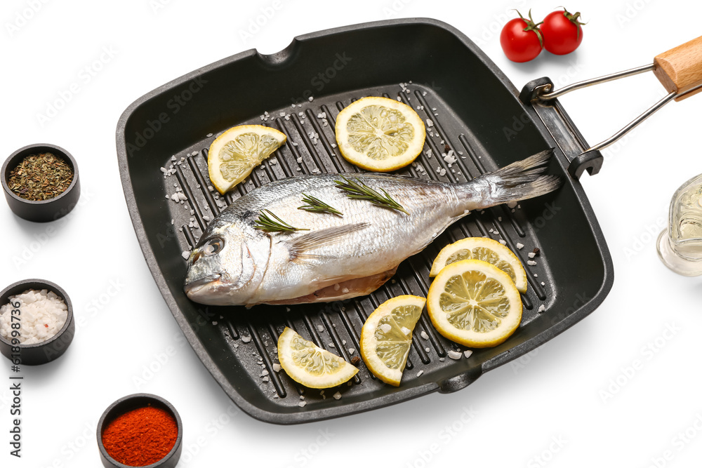 Grill pan of raw dorado fish with lemon and spices and on white background