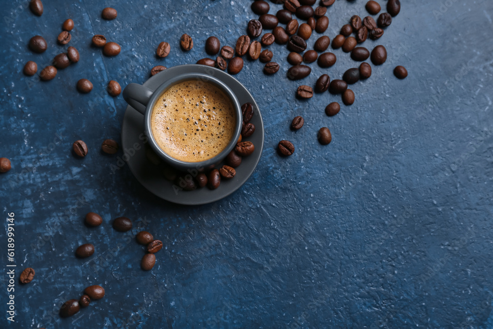 Cup of hot espresso and coffee beans on blue background