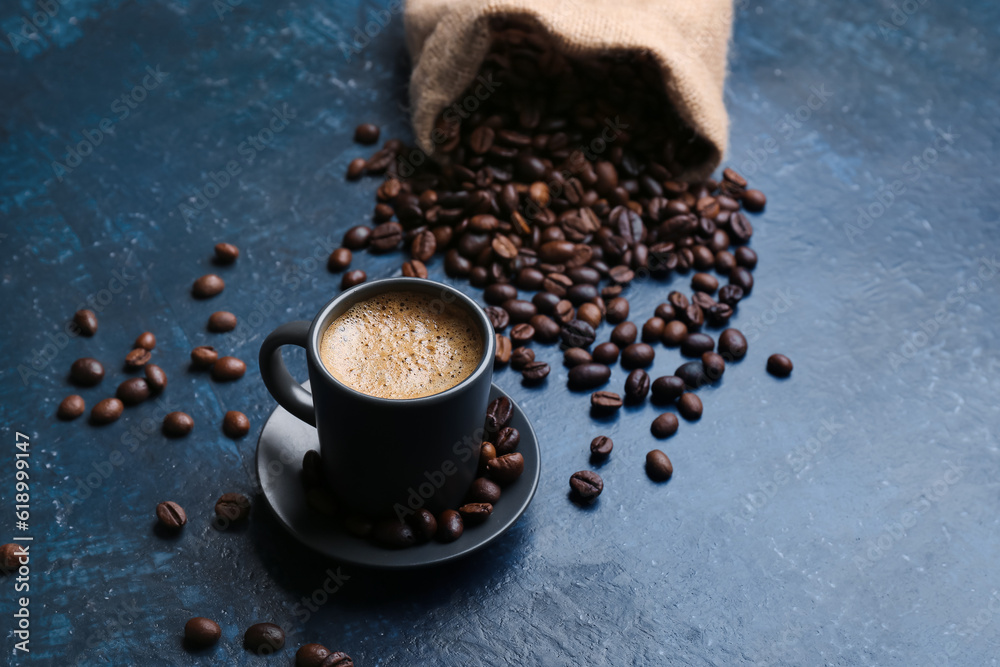 Cup of hot espresso and sack bag with coffee beans on blue background